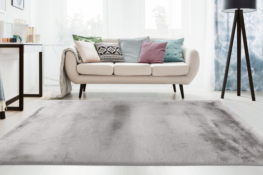 White round carpet in bright living room with lamp and ladder near sofa with pillows